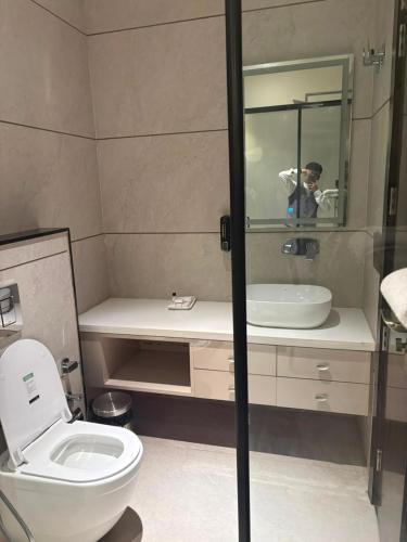 a man taking a picture of a bathroom with a toilet and sink at Besstin Hotel in Hisār