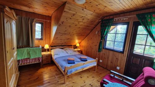 a bedroom with a bed in a wooden cabin at Domek pod Lasem in Płaska