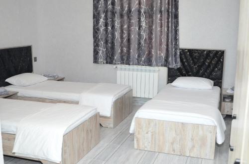 a room with three beds and a window at Seki Qonaq Evi in Sheki