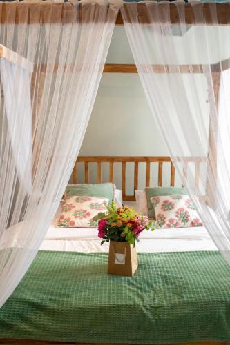 Ein Schlafzimmer mit zwei Betten, Vorhängen und einer Blumenvase. in der Unterkunft Suites Wellness à Sprimont - Logements avec jacuzzi pour 2 personnes in Sprimont