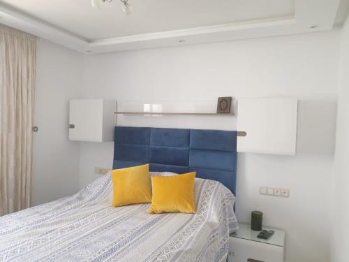 a bedroom with a bed with two yellow pillows at Appart Cosy in Fnidek