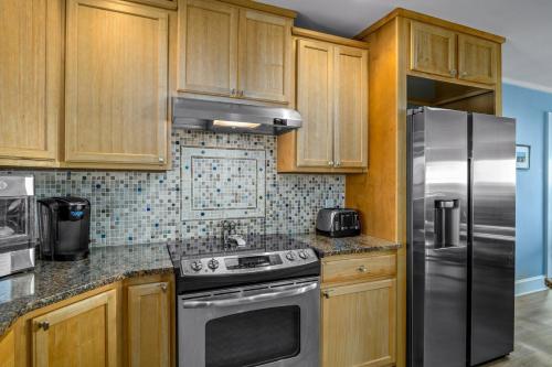 a kitchen with wooden cabinets and a stainless steel refrigerator at Ohana in Holden Beach