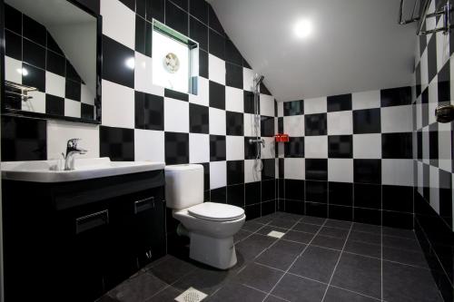 Baño en blanco y negro con aseo y lavamanos en The Bala's Holiday Chalet en Cameron Highlands