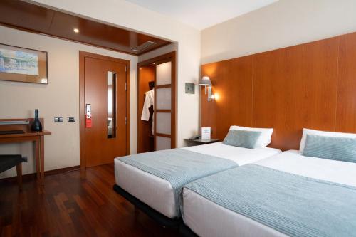 a hotel room with two beds and a desk at Hotel Ciutat Martorell in Martorell