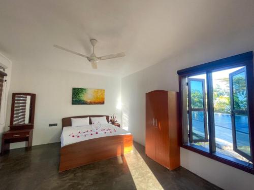 a bedroom with a bed and a large window at Whisky Point Surf Cabanas in Ampara