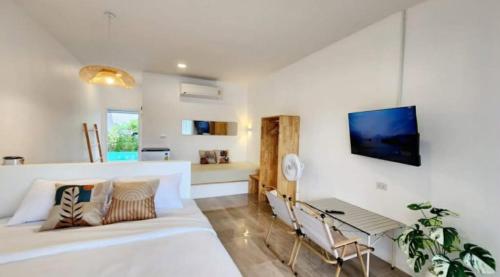 a living room with a white bed and a tv at บ้านลำฟาร์มสเตย์แอนด์คาเฟ่ สระบุรี in Ban Nong Ta Bun