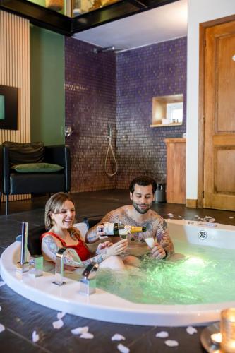 Ein Mann und eine Frau sitzen in einer Badewanne in der Unterkunft Suites Wellness à Sprimont - Logements avec jacuzzi pour 2 personnes in Sprimont