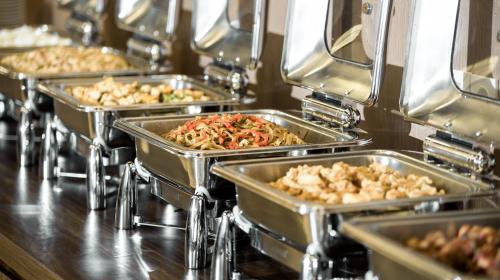 a row of trays filled with different types of food at Hotel Chanti Managed by TENTREM Hotel Management Indonesia in Semarang