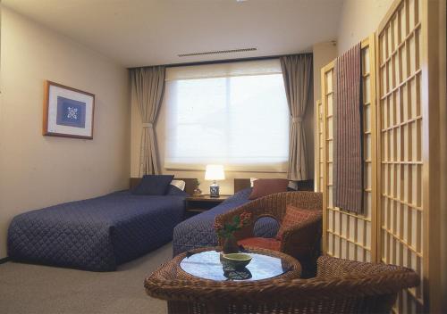a hotel room with a bed and a couch and a table at 旅館かわな -Ryokan Kawana- in Kimitsu
