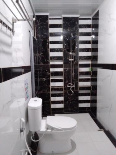 a bathroom with a toilet and a black tile wall at BIN DAOD Hotel Syariah in Meulaboh