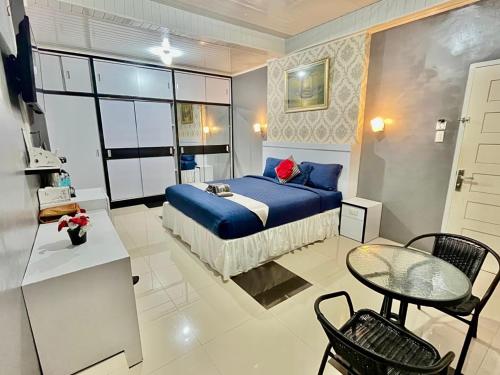 a bedroom with a blue bed and a table and chairs at BIN DAOD Hotel Syariah in Meulaboh