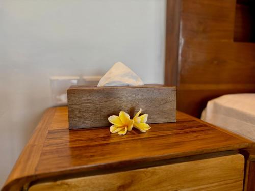 a wooden table with a yellow flower on it at Atta Residence by Manara in Seraya