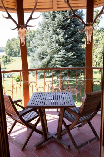 a table and two chairs on a porch with deer heads at Hárs Fogadó in Ötvös
