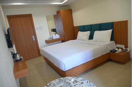 a bedroom with a large bed and a television at Shubhratna Hotel & Resort in Ujjain