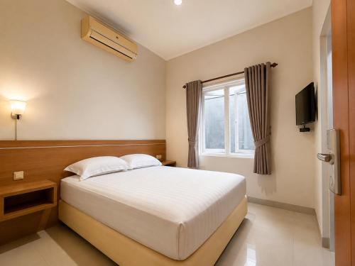 a bedroom with a white bed and a window at Wisma Pelangi 5 in Jakarta