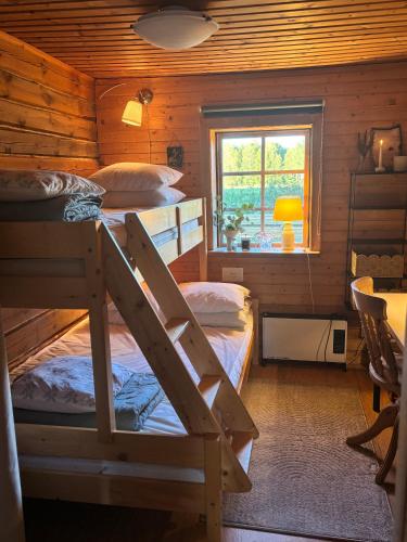 a bedroom with two bunk beds and a window at Mysig timmerstuga med sjötomt in Grangärde