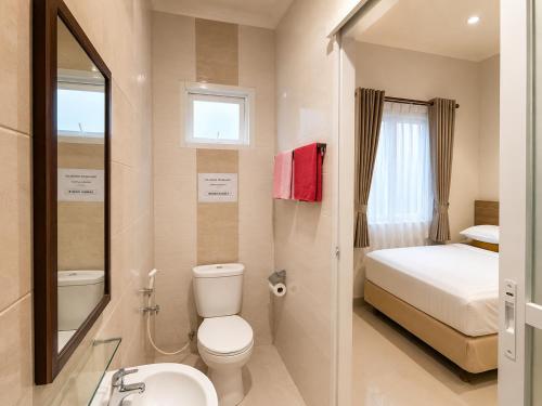 a bathroom with a toilet a sink and a bed at Wisma Pelangi 5 in Jakarta