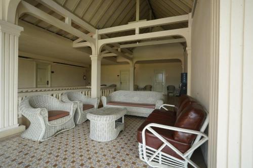 a porch with wicker chairs and a couch and tables at Hotel Grand Rosela in Yogyakarta