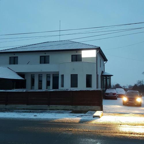 a white building with cars parked in a parking lot at Pensiunea Aurelia in Şiria