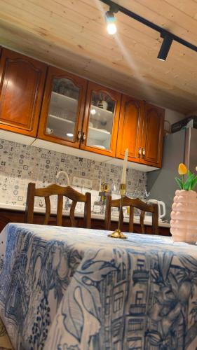 a kitchen with a table with chairs and wooden cabinets at Zhorzholiani House - Betkili in Lakhiri