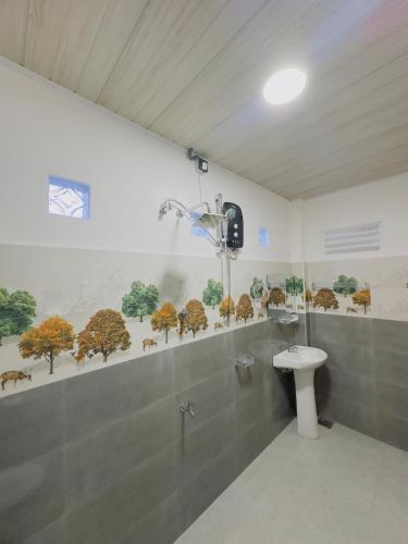 a bathroom with a toilet and trees on the wall at Misty Garden in Maskeliya