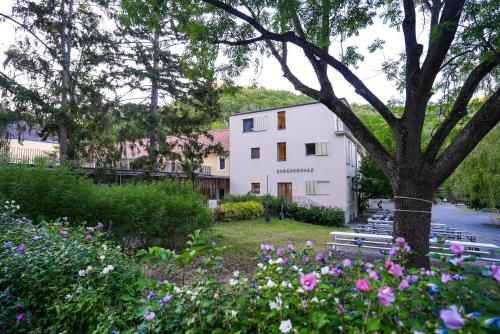 a building with benches and a tree and flowers at Mátraverebély-Szentkút Nemzeti Kegyhely in Mátraverebély