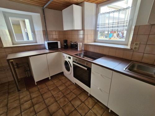 a kitchen with white cabinets and a sink and a dishwasher at Hofruhe in Neresheim