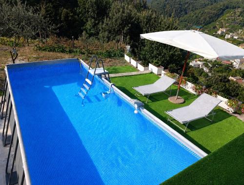 a swimming pool with an umbrella and two chairs and an umbrella at Casale Gelsi in Maiori