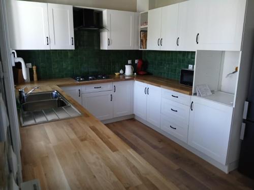 a kitchen with white cabinets and a wooden floor at Maison Marcadieu in Maubourguet