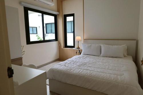 a bedroom with a white bed and two windows at Chiang Rai Home with Full Kitchen in Ban Pa Sang (1)