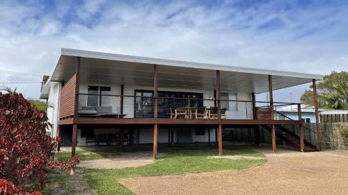 a house with a large deck with a patio at JJ s Holiday House in Wooli
