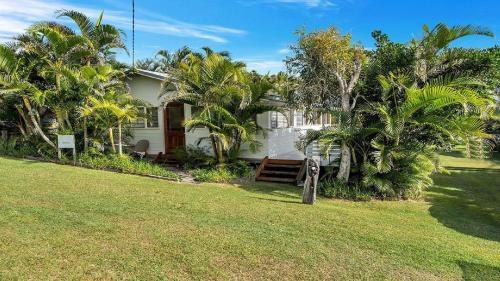 a white house with palm trees in the yard at Tullenderly in Wooli