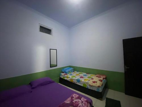 a small bedroom with two beds and a mirror at Homestay Wijaya Mulya in Magelang