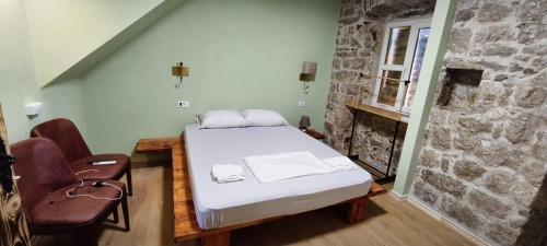 a bedroom with a bed and a stone wall at Palazzo Gabela in Risan