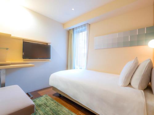 a bedroom with a bed and a flat screen tv at Hotel Resol Ikebukuro in Tokyo