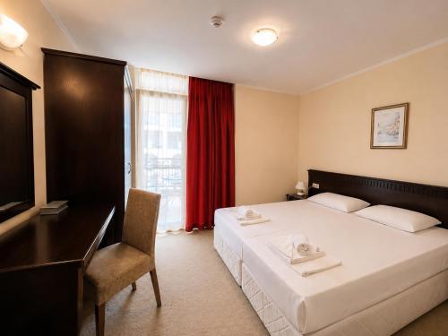 a bedroom with a bed and a desk and a window at Красавиците тъмнокоси Sunset Family in Pomorie