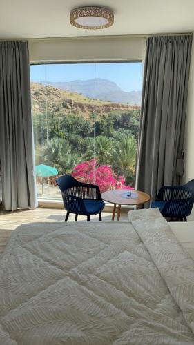 a bedroom with a bed and a table and a large window at Wadi Bani Khalid Guest house in Dawwah