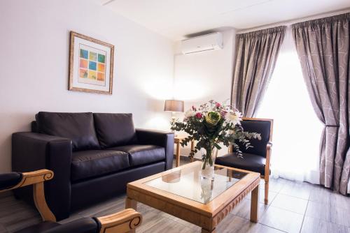 a living room with a couch and a table with flowers at Airport Inn and Suites in Johannesburg