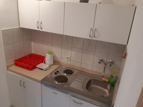 a small kitchen with a sink and white cabinets at Apartman Jednosoban, Dvosoban, Trosoban in Sukošan