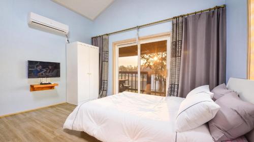 a bedroom with a white bed and a window at Samcheok Good Friend Pension in Samcheok