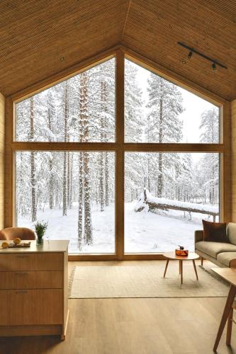 a living room with a large window with snow covered trees at Ainur Villas in Saariselka
