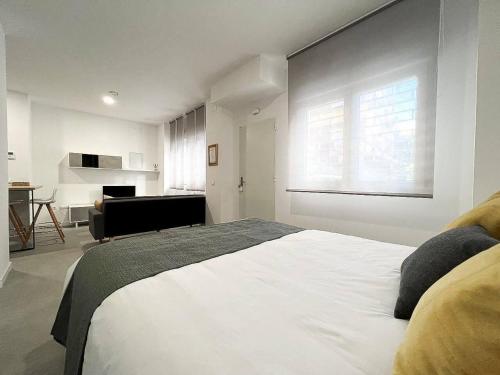 a bedroom with a large white bed with a window at Studio Alborán in Málaga