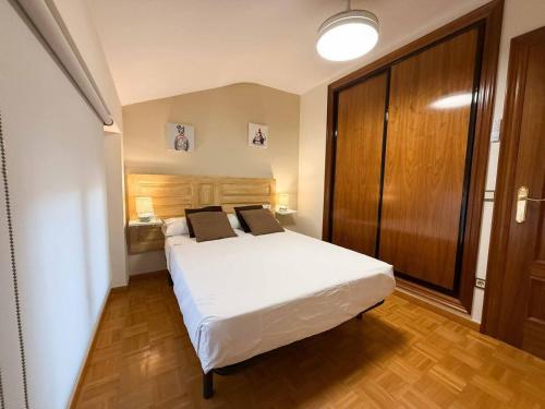 a bedroom with a white bed and a wooden cabinet at Placituela 7 in San Esteban de Gormaz