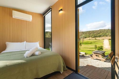 a bedroom with a bed and a sliding glass door at The Wollombi Wanderer by Tiny Away in Wollombi