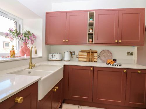a kitchen with red cabinets and a sink at Evansford in Ballater
