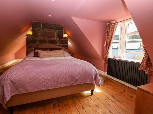 a bedroom with a bed with purple sheets and a window at Evansford in Ballater