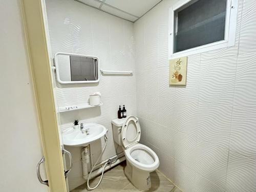 a white bathroom with a toilet and a sink at Comfy hotels Suvarnabhumi in Suvarnabhumi Airport