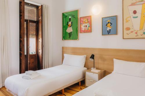 two beds in a room with paintings on the wall at La Casona Beach House in Valencia