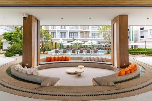 a lobby with orange chairs and tables and a building at Radisson Resort Layan Phuket in Layan Beach