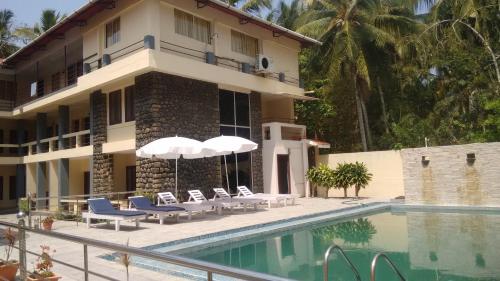 a resort with a swimming pool and chairs and a building at New Kovalam Beach Hotel in Kovalam